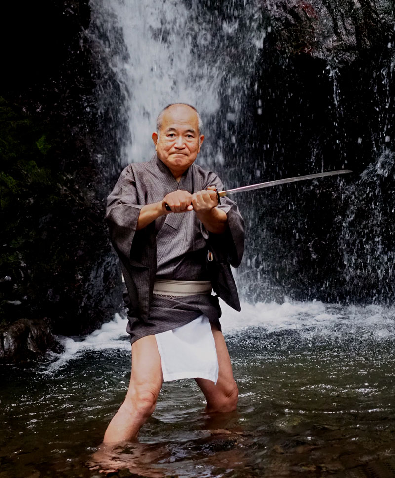 滝壺の中で侍の気分になりきり、剣を中段に構える和田爺