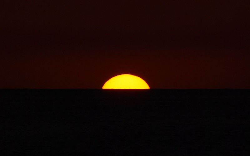 水平線に没する黄色に変化した太陽　19:03