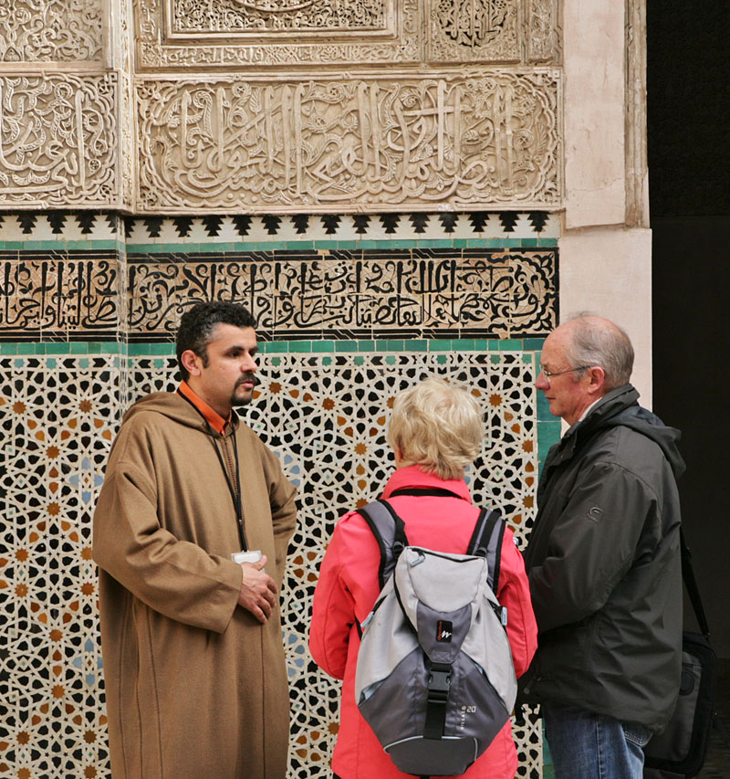 ジュラバを着たモロッコ人の話を聞く観光客
